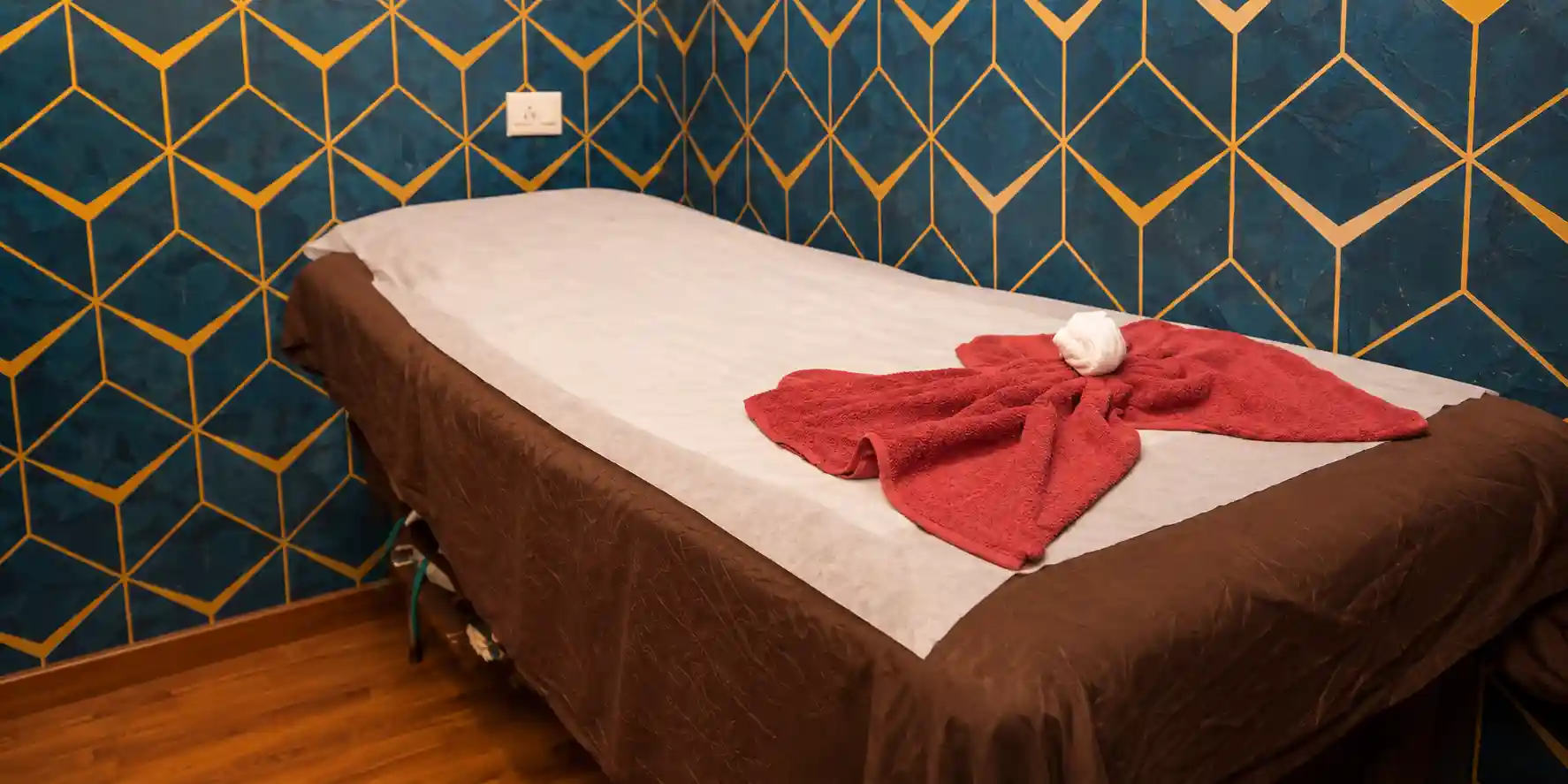 Massage table with a folded towel in a blue and gold room